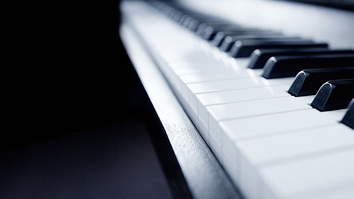 Close-up of piano keys, black and white, with focus on white keys.