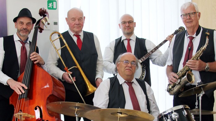 Et jazzband i formelt tøj, der spiller på instrumenter som trompet, saxofon, trommer og kontrabas.
