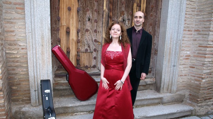 Klassische Musiker posieren mit einem Cellokoffer und einer Gitarre auf einer rustikalen Steintreppe.