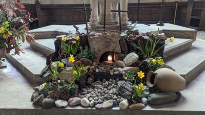 Small garden with rocks, flowers, and cross in a church setting