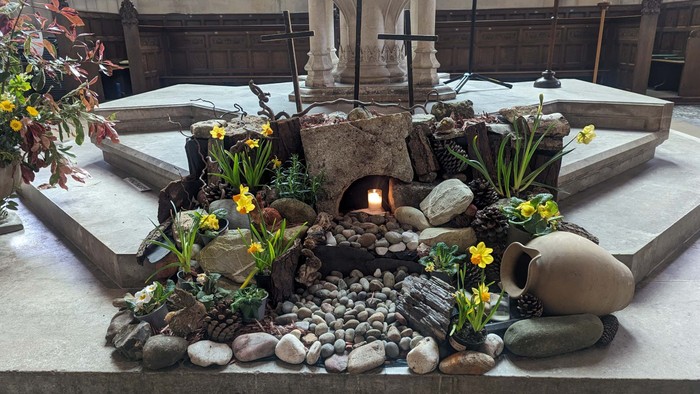 Small garden with rocks, flowers, and cross in a church setting