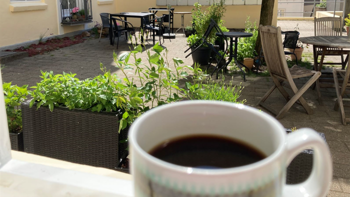 En kaffekop på en bord i en træterrasse med bord og stoler.