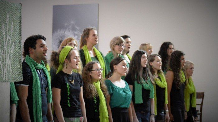 Ein Chor singt, alle tragen grüne Schals