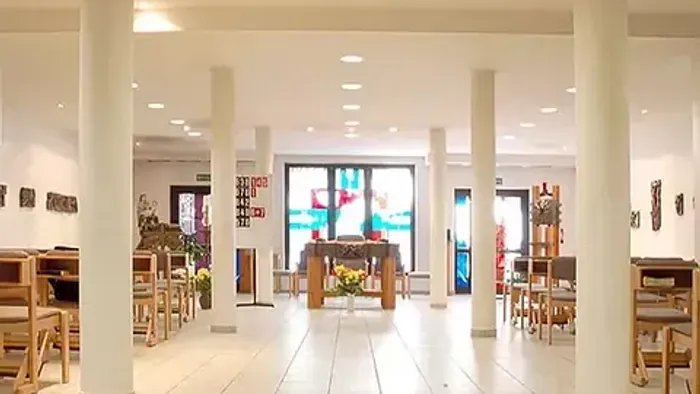 Modernes Café mit hohen Säulen und hellen Farben, Holzstühle und Tische, große Fensterfront