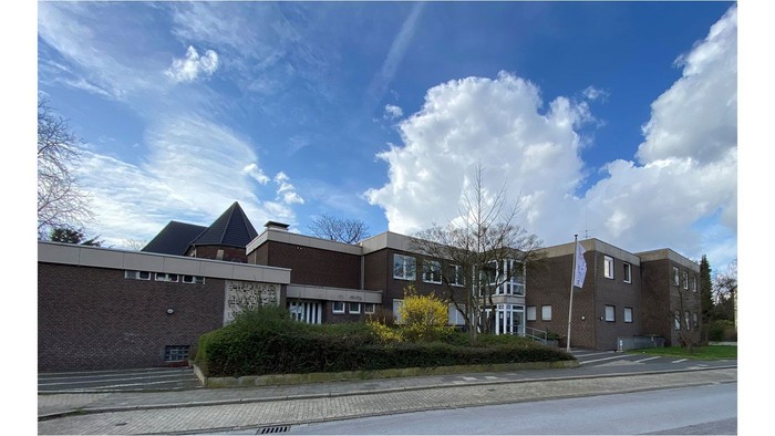 Moderne Wohngebäude mit großen Fenstern und einem klaren blauen Himmel mit weißen Wolken.