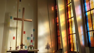 Farbenfrohe Kirchenfenster mit Kreuz und Altar.