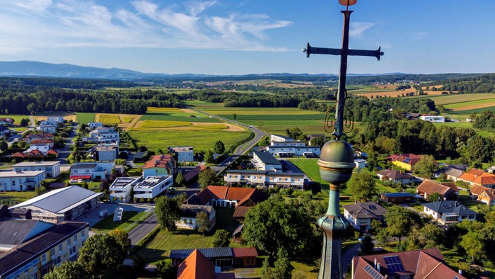 Luftaufnahme eines malerischen Dorfes, eingebettet in eine malerische Landschaft mit einem markanten Kirchturm.