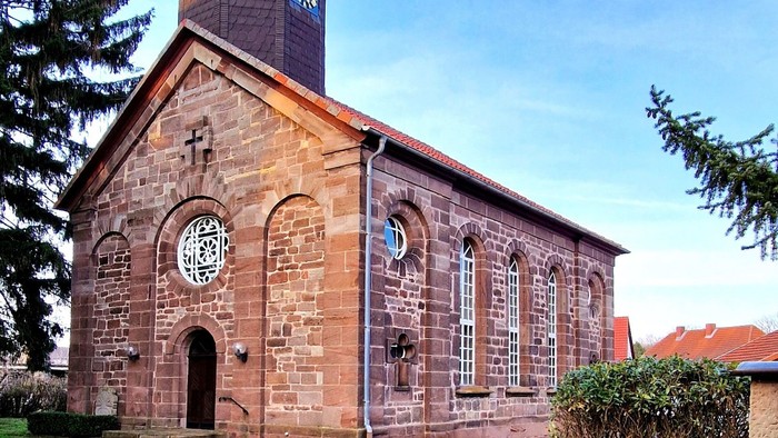 Steinkirche mit Uhrturm und Rundbogenfenstern.