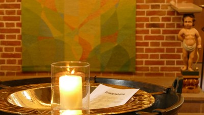 Kerze auf Metalltablett vor abstraktem Bild