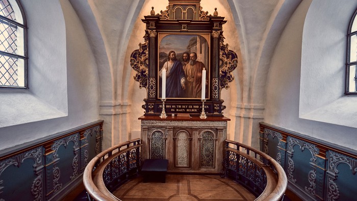En indre kirkerum med alter og maleri.