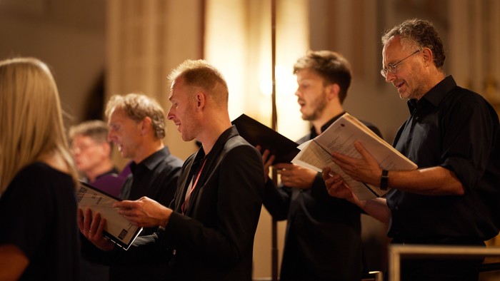 Ein Chor, der mit Notenblättern probt oder auftritt, konzentriert und engagiert in einem Konzertumfeld.