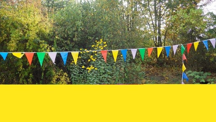 Bunte Fähnchen vor gelber Wand und grünem Hintergrund