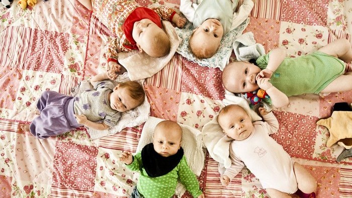 En gruppe børn og dyr ligger på en blomsteret dekke.