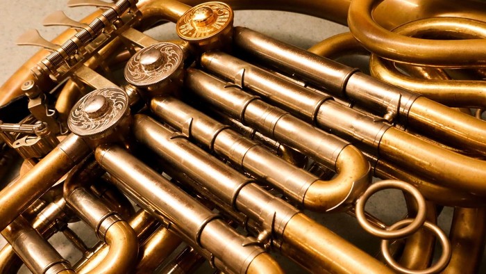 Ein goldenfarbener French Horn mit komplexen Rohrleitungen und Ventilen