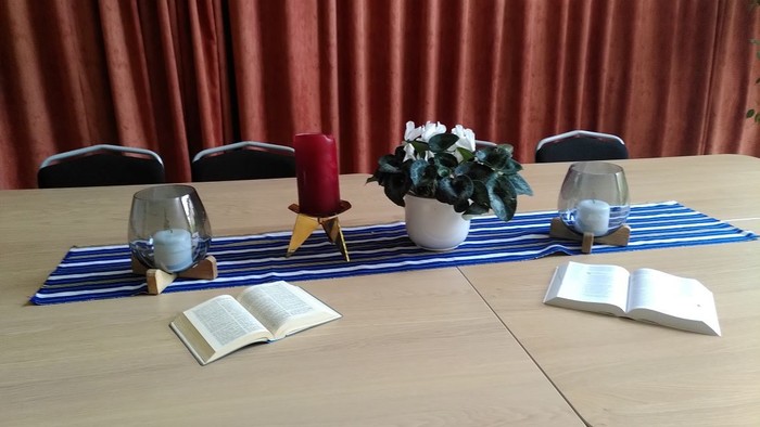 Ein Tisch mit blauem Tischläufer, Kerzen, Blumen und aufgeschlagenen Büchern