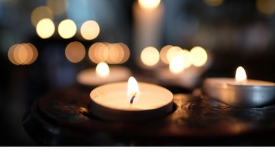 Warm beleuchtete Kerzen auf einer dunklen Holzoberfläche mit weichem Bokeh-Licht im Hintergrund.