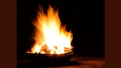 Lebhafte Flammen flackern hell in einer Schale unter einem dunklen Nachthimmel.