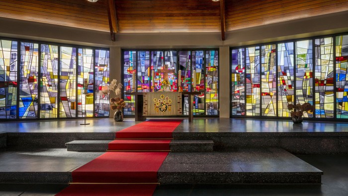 Kircheninneres mit Buntglasfenstern und rotem Teppichgang