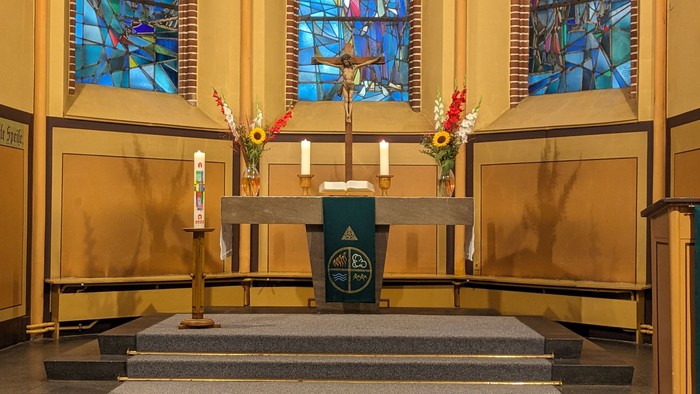 Altar der Magdalenenkirche mit Kreuz, Kerzen, Blumenschmuck und grünem Parament.