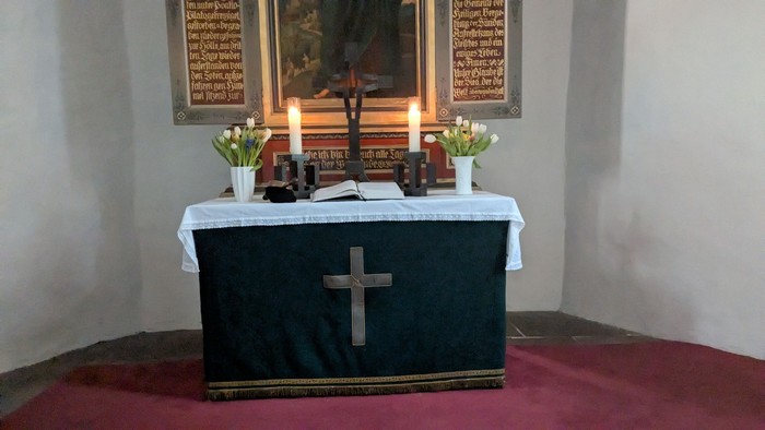 Altar mit Kreuz zwei Kerzen Blumen