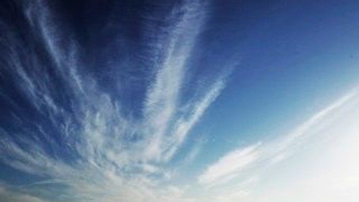 En klar himmel med spredte, hvide skyer.