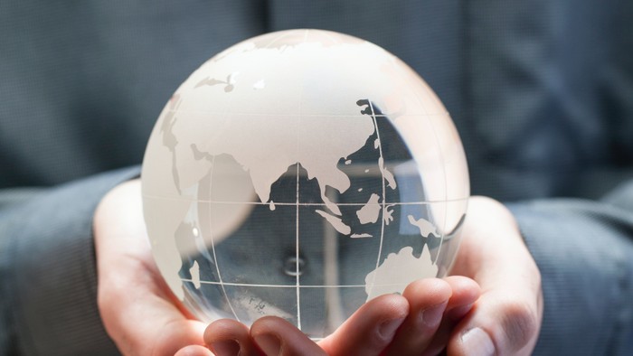 Hands holding glass globe with world map.