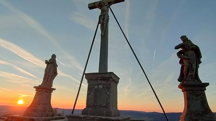 Kreuz mit Statuen, Sonnenuntergang im Hintergrund