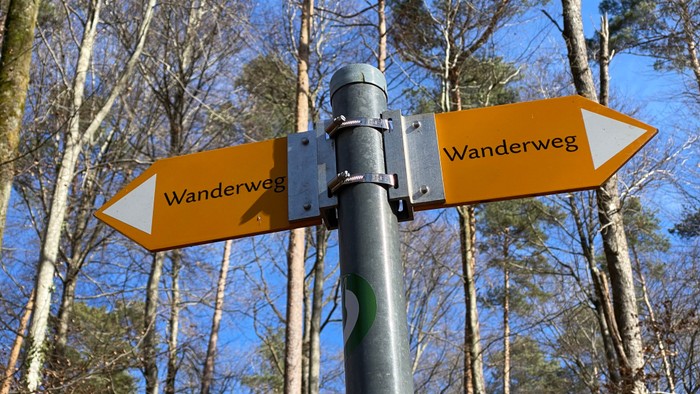 Wanderweg-Schilder an einem Pfosten in einem Wald