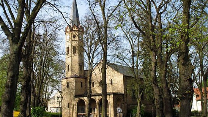 Alte Kirche umgeben von Bäumen in Parklandschaft