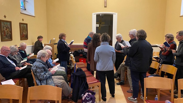 En gruppe mennesker samlet i en kirke med salmebøger, der deltager i en gudstjeneste eller et religiøst møde.