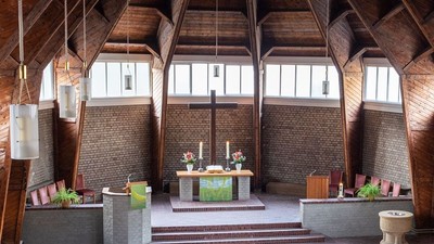 Ein moderner Wohnraum mit hohen Decken und großen Fenstern, eingerichtet mit Holz und grünen Akzenten.
