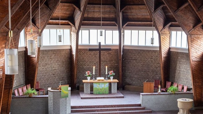 Ein moderner Wohnraum mit hohen Decken und großen Fenstern, eingerichtet mit Holz und grünen Akzenten.