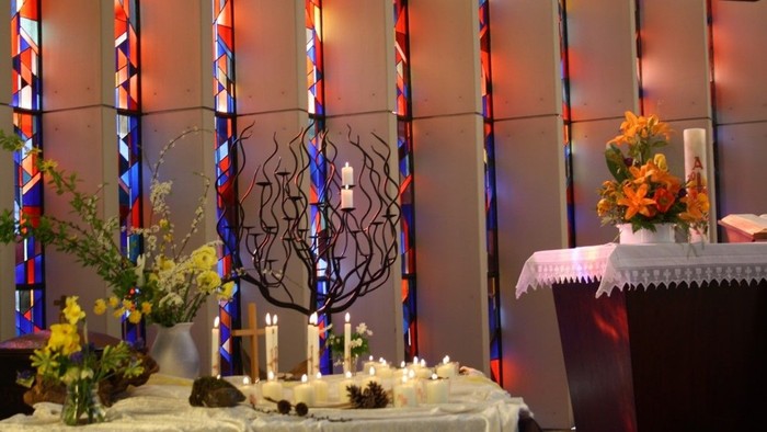 Festlich gestalteter Tisch mit Blumen und Kerzen neben Altar