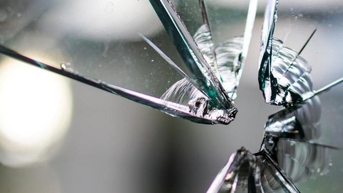 Ein zerbrochenes Glas mit mehreren Rissen und Splittern.