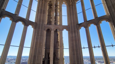 Gotischer Kathedraleninnenraum mit hoch aufragenden Buntglasfenstern und einem panoramischen Blick auf die Stadt darunter.