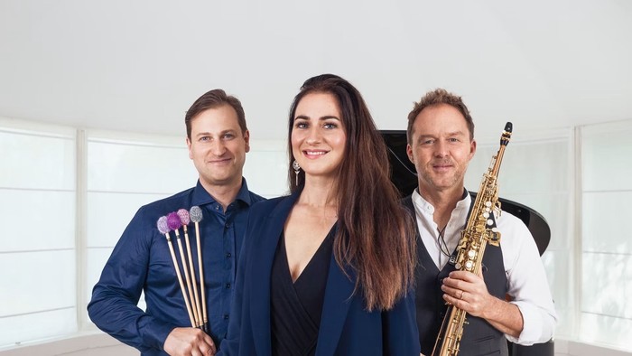 Musikere med køller, saxofon og vibrafon poserer smilende sammen i et studie.