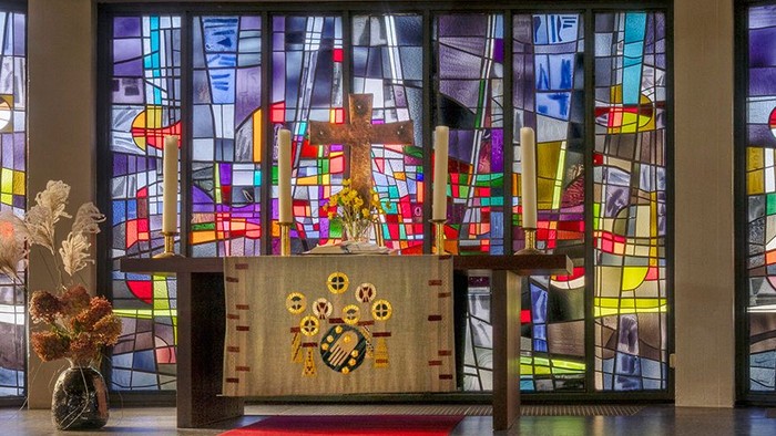 Kircheninneres mit Buntglasfenstern und rotem Teppichgang