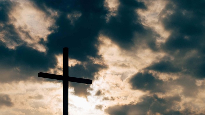 Ein Kreuz vor einem bewölkten Himmel