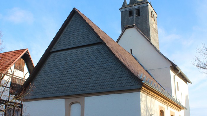 Außenansicht der evangelischen Kirche in Viesebeck. Weiß verputztes Kirchenschiff mit dunklem Dach und Turm mit schieferverkleideter Spitze.