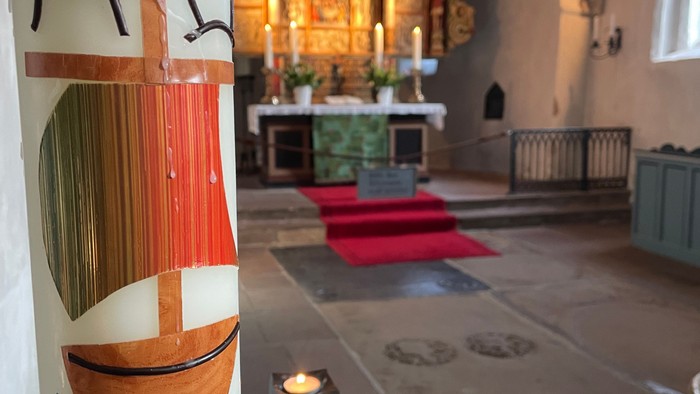 Bunt bemalte Säule in Kirche mit brennender Kerze