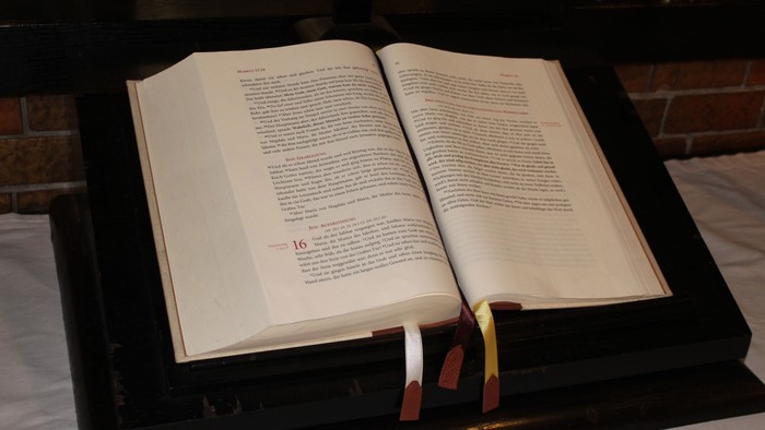 Offene Bibel auf schwarzem Ständer