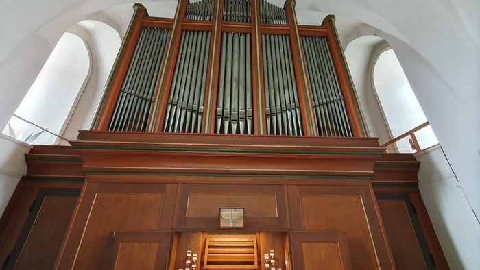 Elegante Holzpfeifenorgel mit mehreren Pfeifenreihen und einer detaillierten Spielanlage unter einem gewölbten Deckengewölbe.