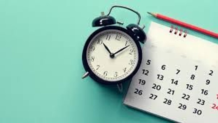 Wecker und Kalender auf grünem Hintergrund