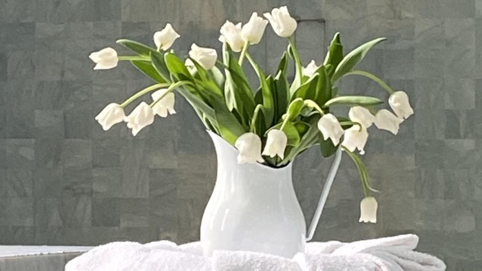 Weiße Tulpen in einer Vase auf einem weißen Sockel