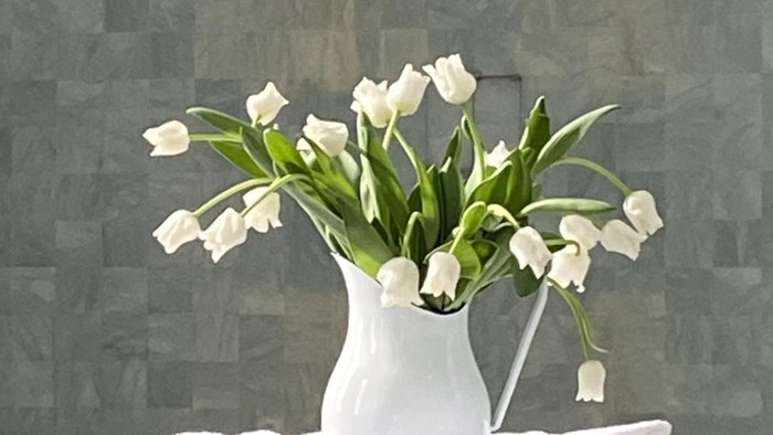 Weiße Tulpen in einer Vase auf einem weißen Sockel