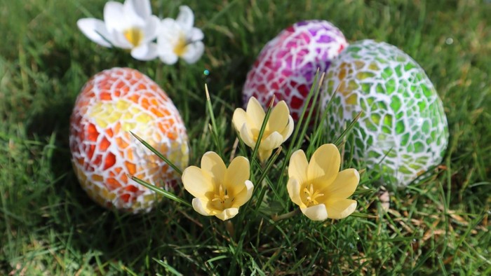 Bunte Ostereier und Frühlingsblumen im Gras