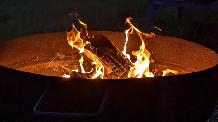 Ein Laptop, der in Flammen in einer metallenen Feuerstelle brennt.