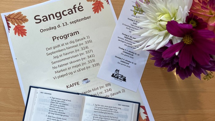Program for Sangcafé den 13. september med blomsterdekor.