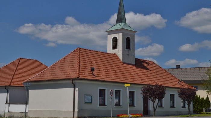 Kirche mit hohem Turm und rotem Dach unter blauem Himmel