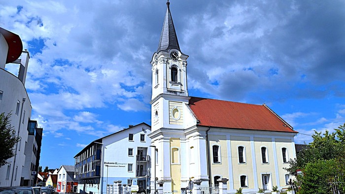 Kirchengemeinde mit weißem Turm und rotem Dach in kleiner Stadt